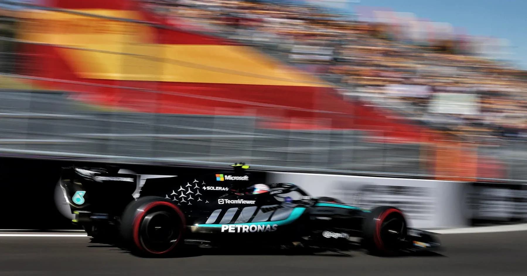 Mercedes car racing past grandstands at event Mercedes car racing past grandstands at event