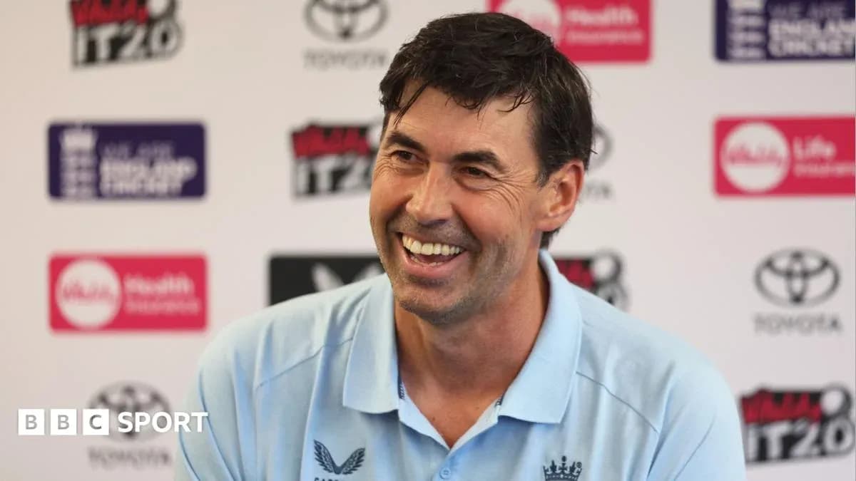 Coach smiling during press conference with logos behind Coach smiling during press conference with logos behind