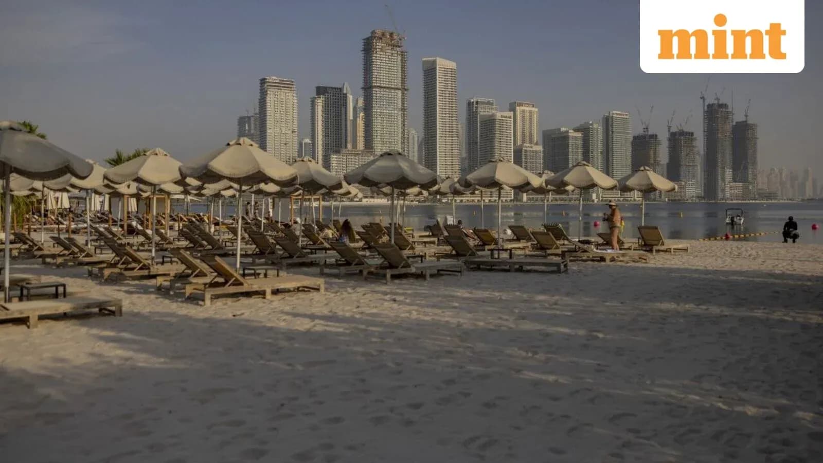 Beach with loungers and city skyline in background Beach with loungers and city skyline in background