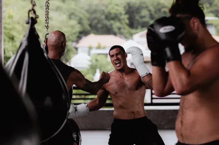 Boxers training with punching bags in gym Boxers training with punching bags in gym