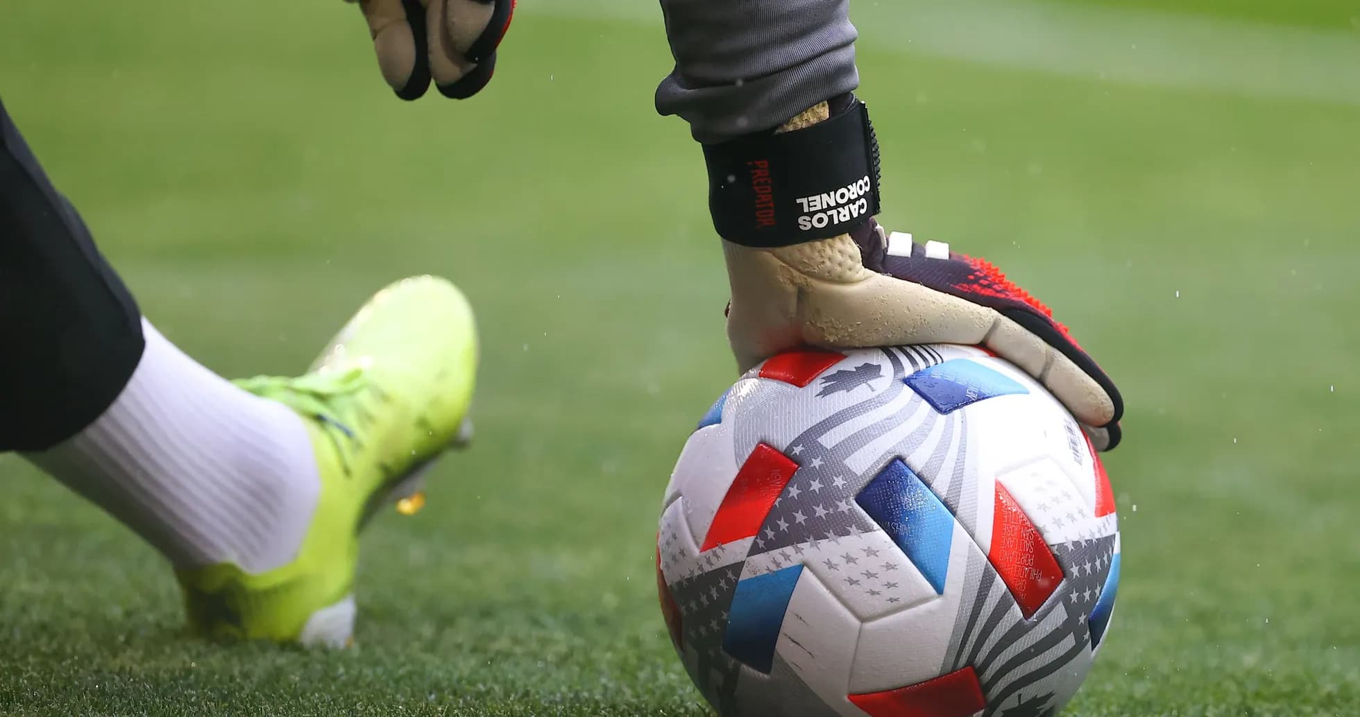 Goalkeeper placing hand on soccer ball on pitch Goalkeeper placing hand on soccer ball on pitch